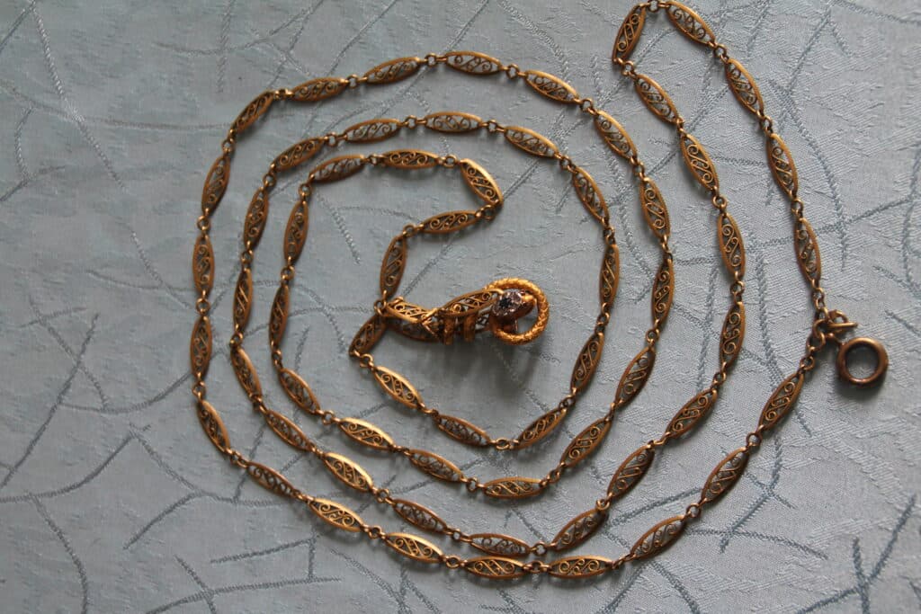 Estimation d’un sautoir en or filigrané et bride serpent sertie de roses Estimation d’un sautoir en or filigrané et bride serpent sertie de roses